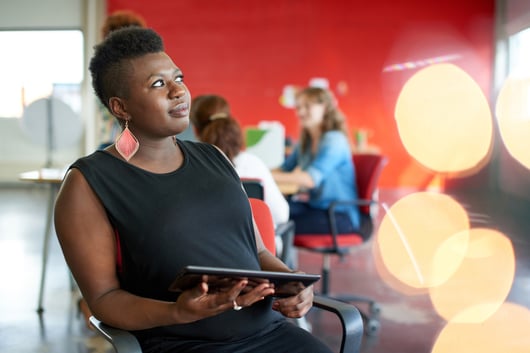 Confident female designer working on a digital tablet in red creative office space