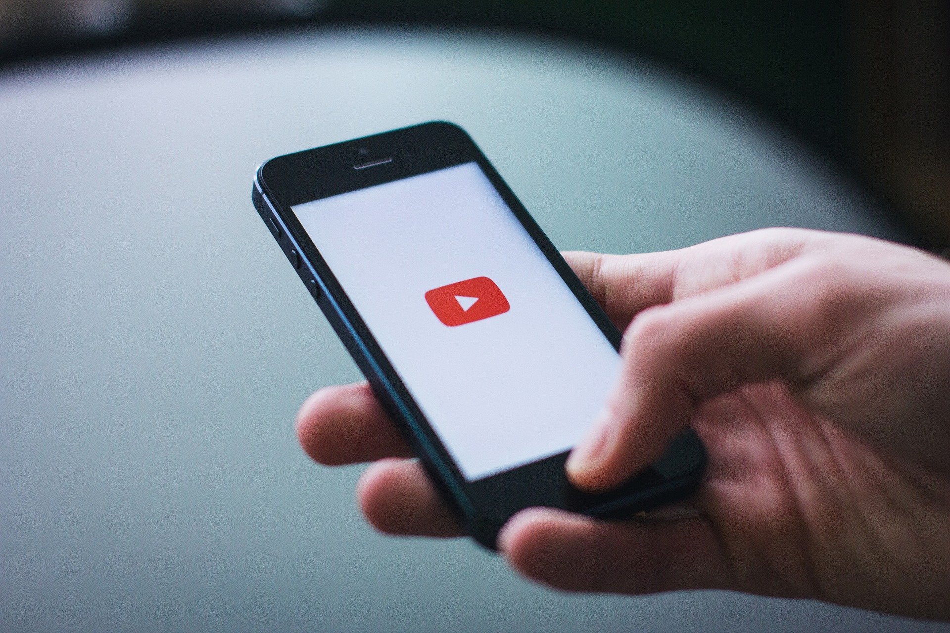 Person holding iPhone with YouTube app