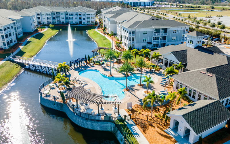 Professional drone photography of an apartment complex with a pool and pond