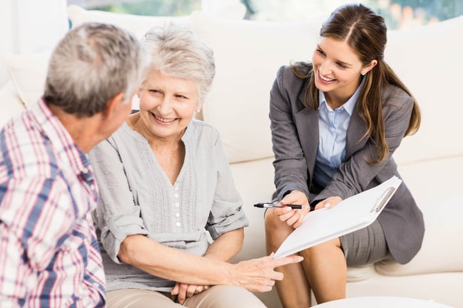 Smiling businesswoman showing documents to senior couple in living room